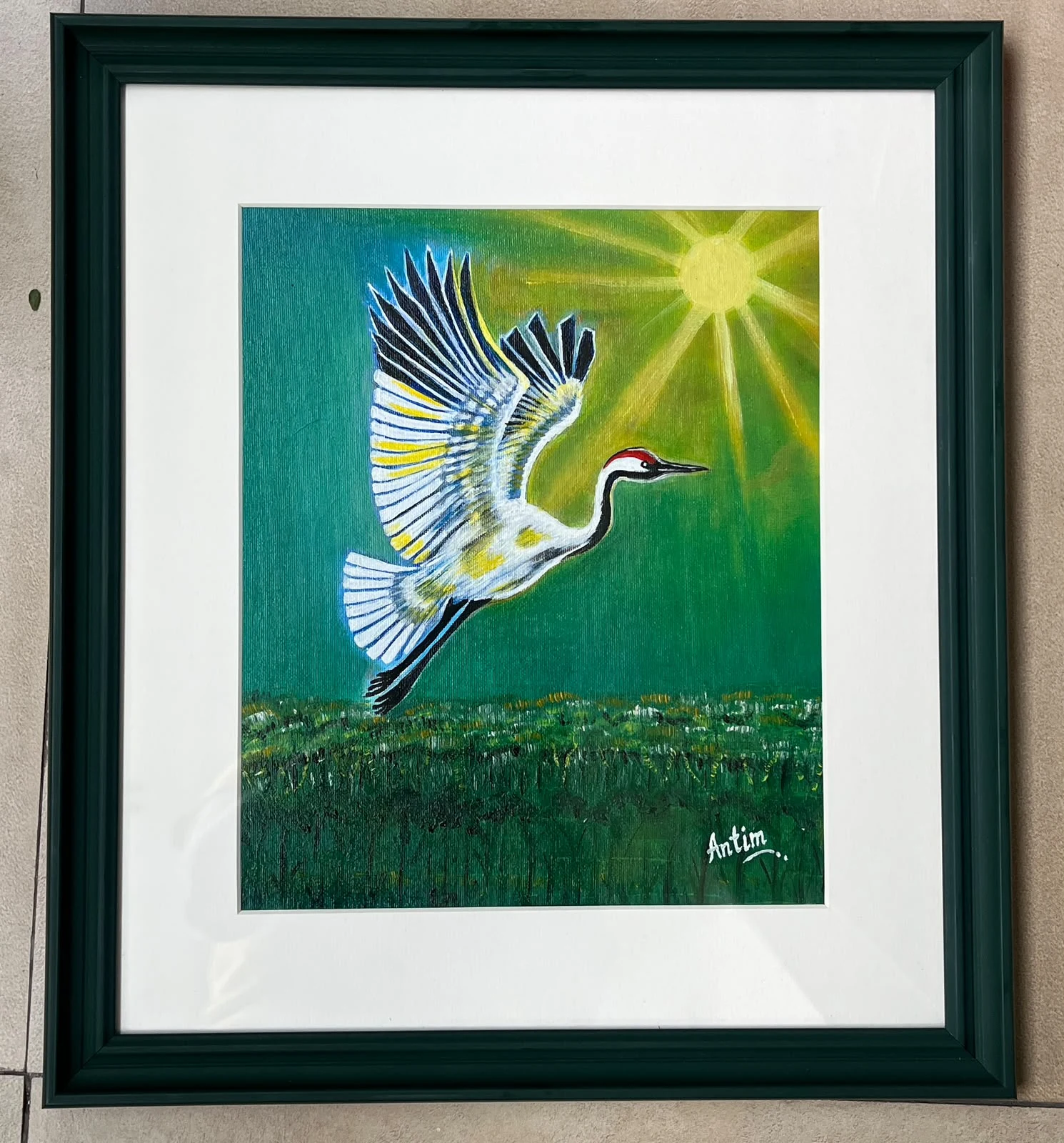 White crane with outstretched wings flying over green wetlands beneath a golden sun, with a white mount and green frame.