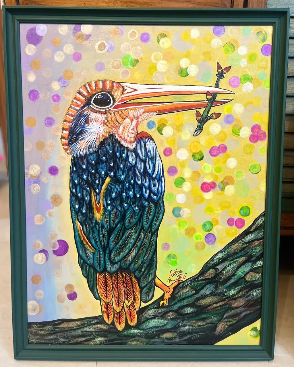 Kingfisher with blue-black feathers and an orange-red beak on a branch, against colourful circles, in a deep green frame.